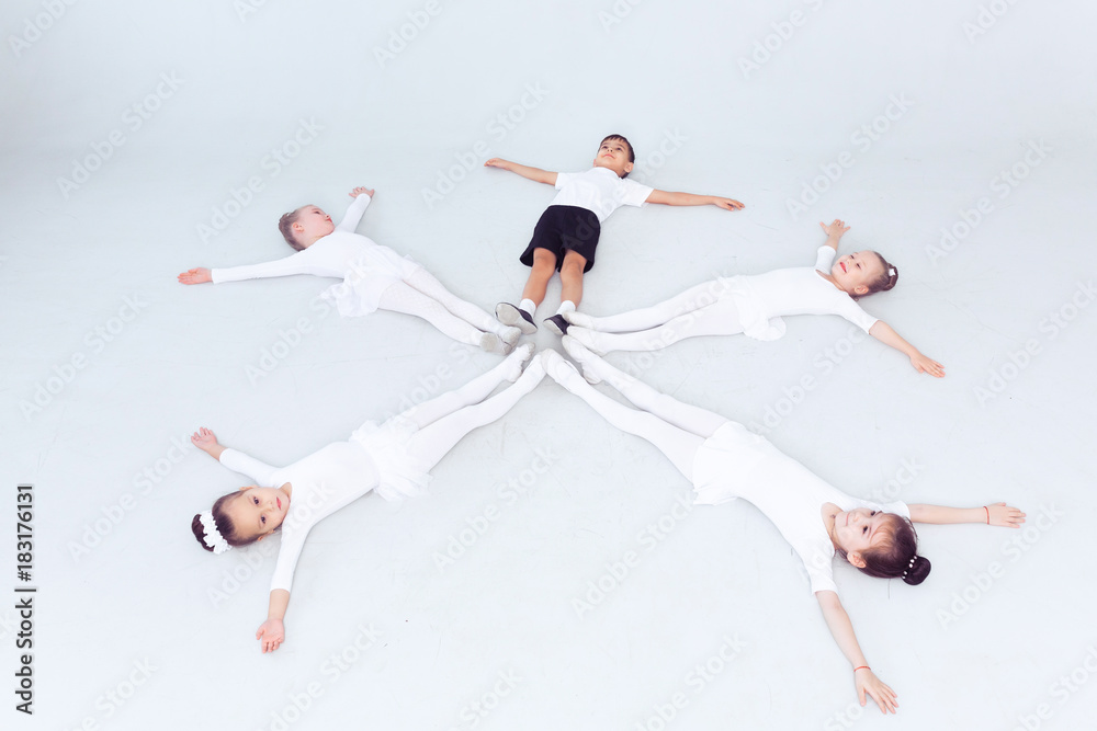 Cute little kids dancers on white background. Choreographed dance by a group of small ballerinas practicing at a classical ballet school