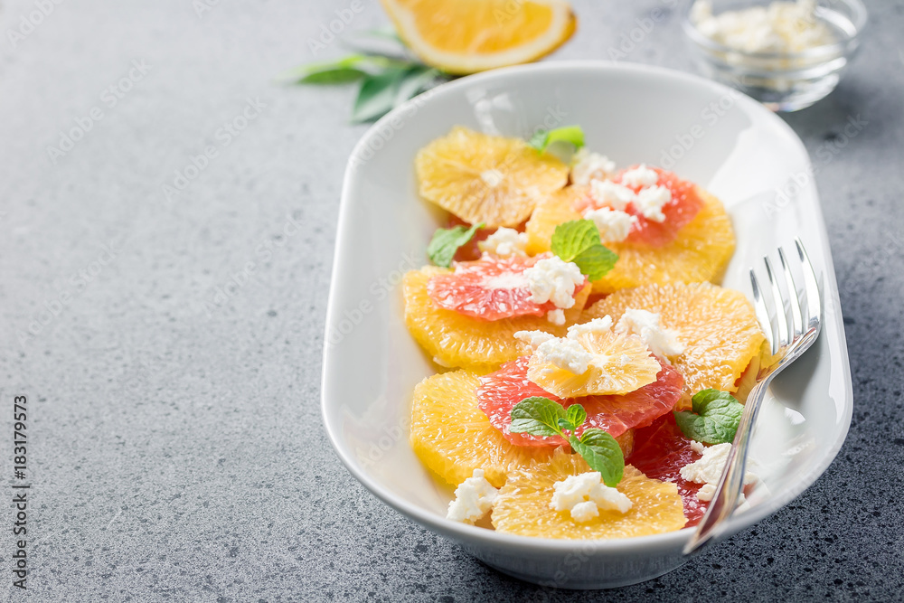 Citrus winter fruit feta mint salad on stone concrete background. Selective focus, copy space. Citrus winter fruit feta mint salad on stone concrete background. Selective focus, copy space.