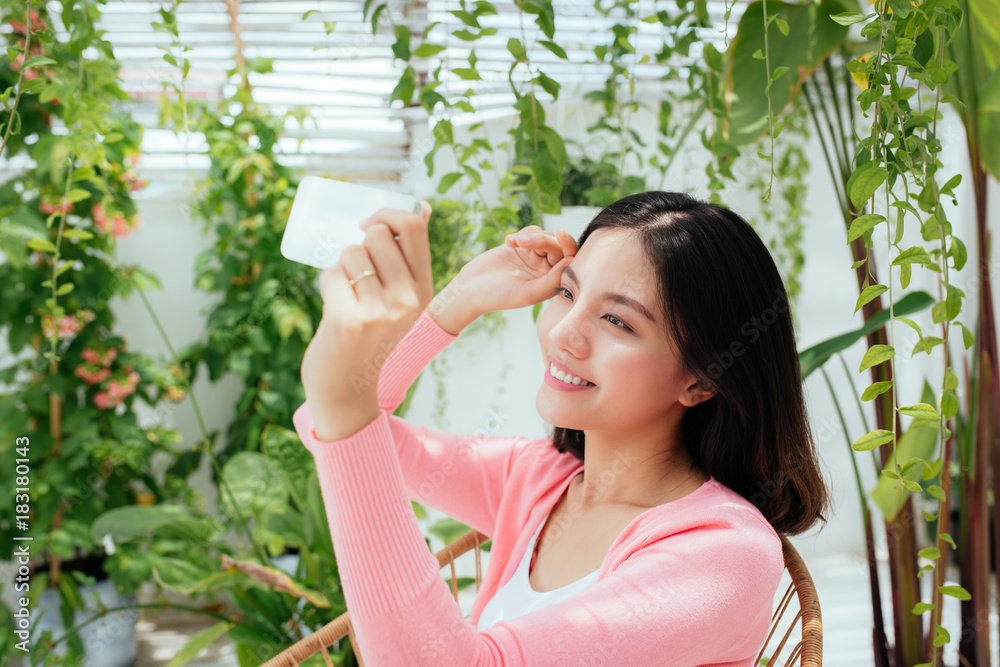 Cute asian girl is taking selfie photos and sitting in sunny garden. Cute asian girl is taking selfie photos and sitting in sunny garden.