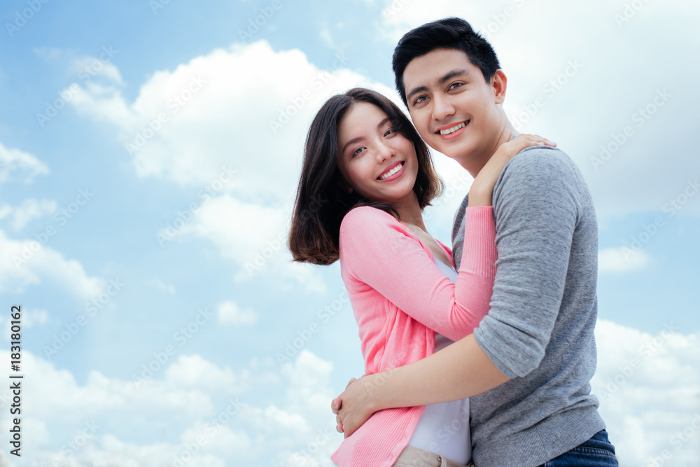 Young beautiful woman and asian man laugh against the dark blue sky with clouds Young beautiful woman and asian man laugh against the dark blue sky with clouds