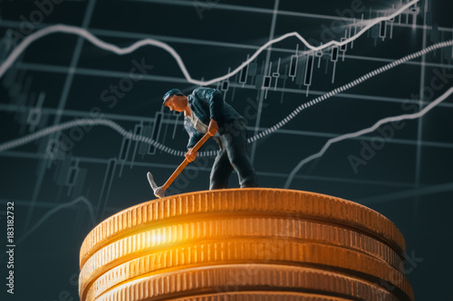 macro miner figurine on shiny bitcoin stack over stock market chart background