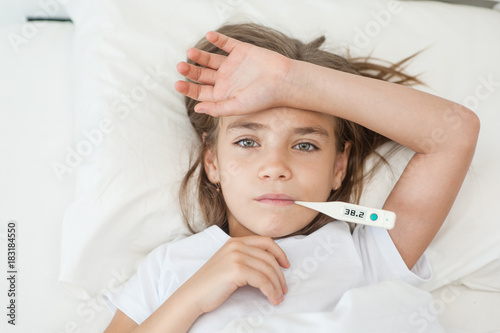 Obraz na plátne sick girl lying in bed with a thermometer in mouth