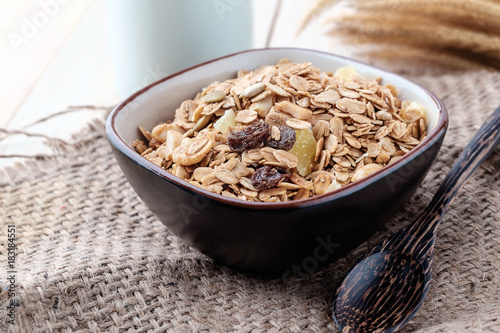 Breakfast cereals with dried fruits in a bowl on a wooden background.
