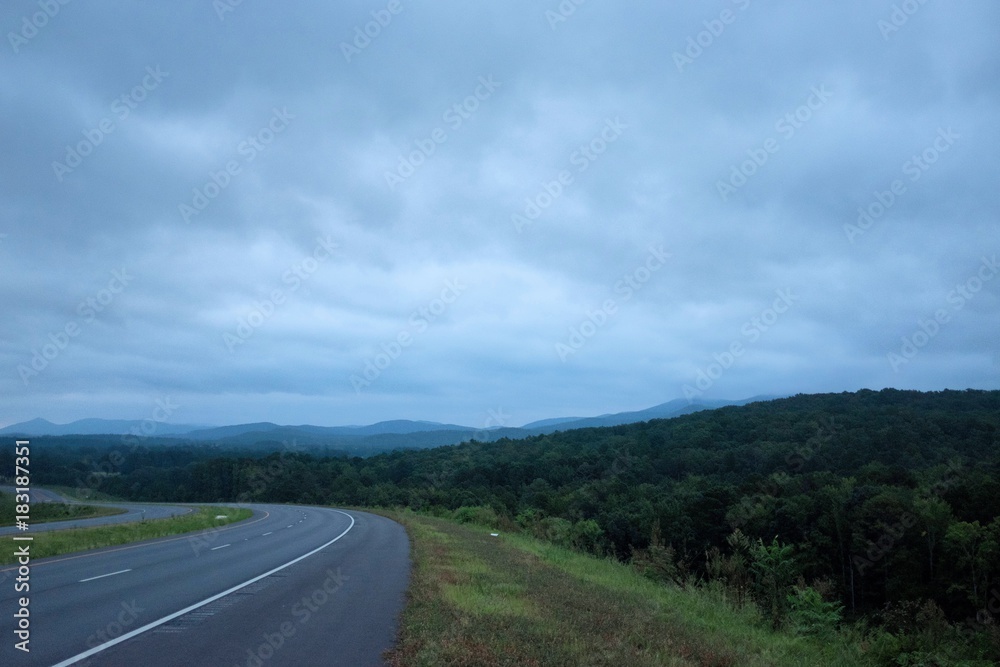 A highway bends toward the foothills on a cloudy late summer morning just before sunrise near Anniston, Alabama, USA
