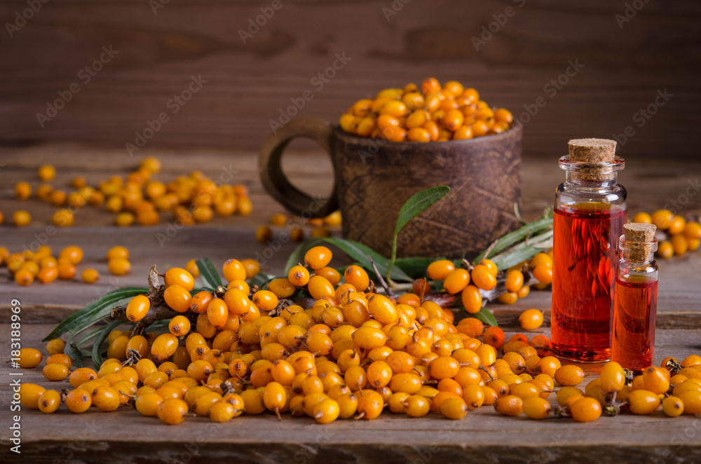 Sea buckthorn and two bottles with sea buckthorn oil on wooden table