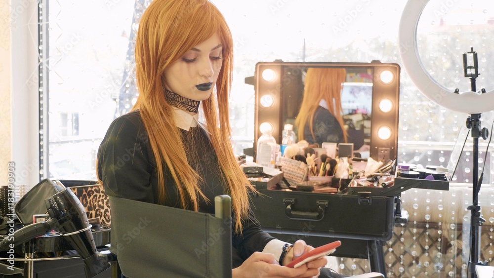 Young beautiful girl with halloween makeup using smart phone at beauty salon Young beautiful girl with halloween makeup using smart phone at beauty salon