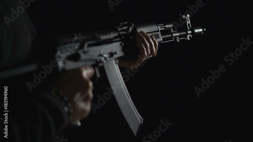 Armed man in black. Bandit with weapons in hand on a black background. The criminal scene. Hands with a gun close-up