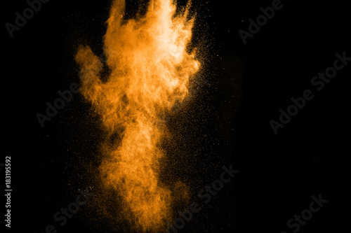 Abstract orange dust explosion on black background. Abstract gold powder splattered on black background. Freeze motion of orange powder clouds splash.