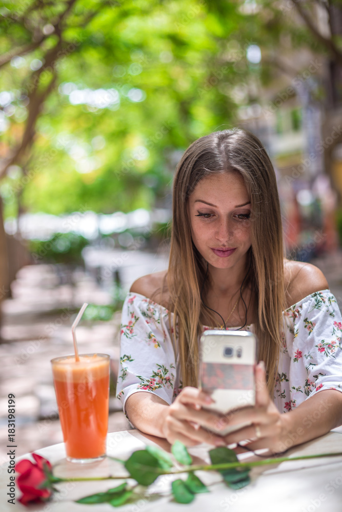 Romantic cute girl is sitting in the cafe and video chatting with red rose on the table. Dating and love concepts. Human emotions. Romantic cute girl is sitting in the cafe and video chatting with red rose on the table. Dating and love concepts. Human emotions.
