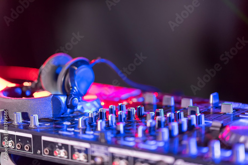 The DJ console cd mp4 deejay mixing desk Ibiza house music party in nightclub with colored disco lights.