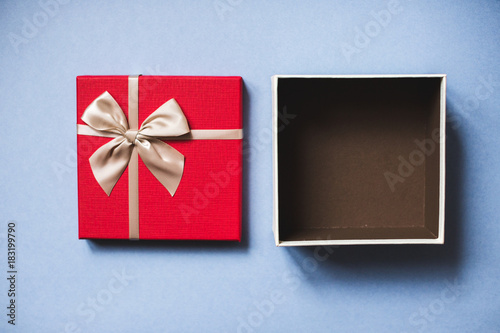 Open red gift with bow on blue background top view.