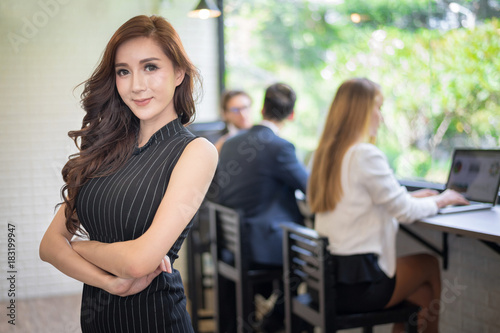 Successful Confident Business Woman Wearing High Class Dress Looking To Camera While Standing Against Blur Business People Working in Coffee Shop