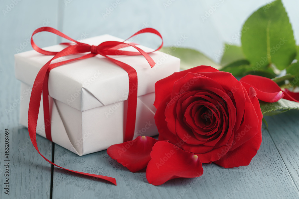 red rose on blue wood table with gift box