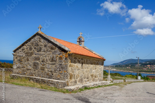 Historic village medieval church by the asphalt road during sunny day, blue sky