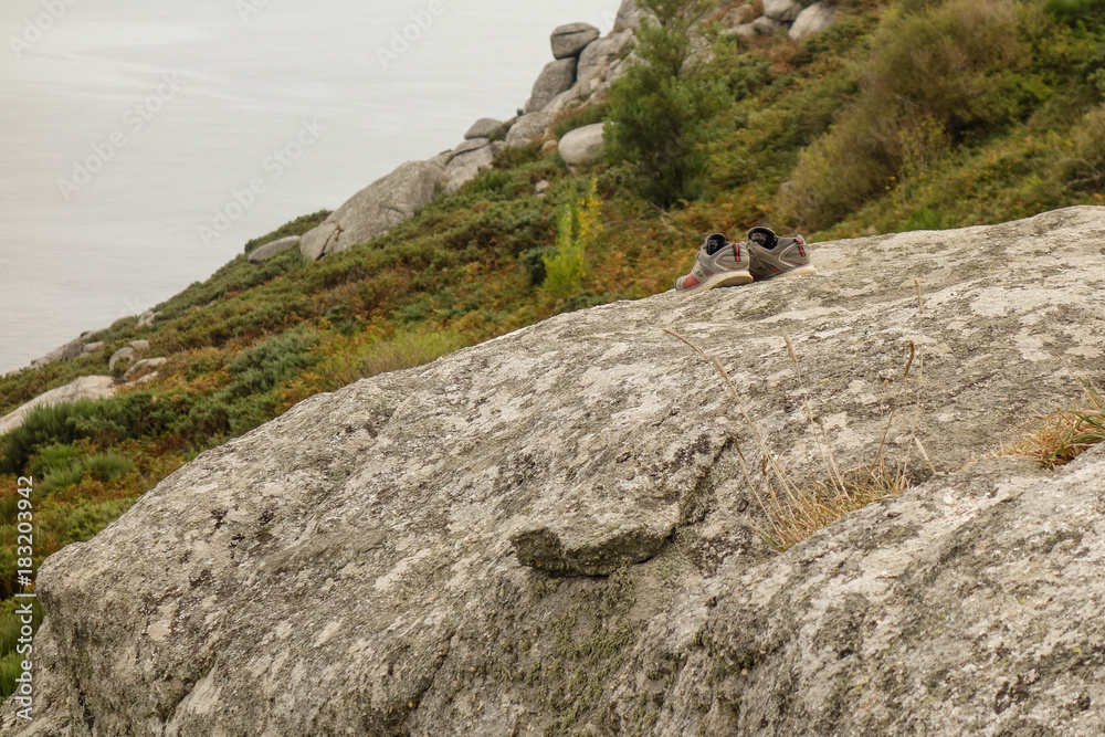 Pair of shoes left on cliff during cloudy day Pair of shoes left on cliff during cloudy day