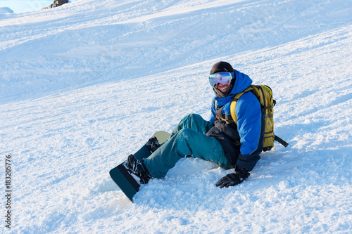 Smiling man snowboarder resting sit