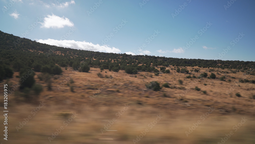 Driving plate side view moving through hills and fields with motion blur