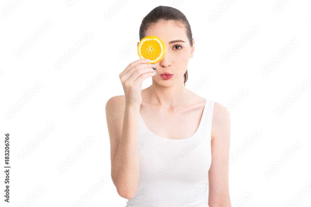 Beautiful woman holding orange slice hiding eye behind isolated on white background Beautiful woman holding orange slice hiding eye behind isolated on white background