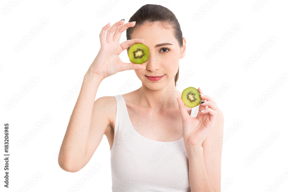 Beautiful woman holding kiwi slice hiding eye behind isolated on white background Beautiful woman holding kiwi slice hiding eye behind isolated on white background