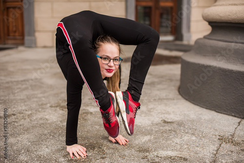 girl gymnast stretching on the street. Young girl acrobat. The girl is engaged in gymnastics. photo