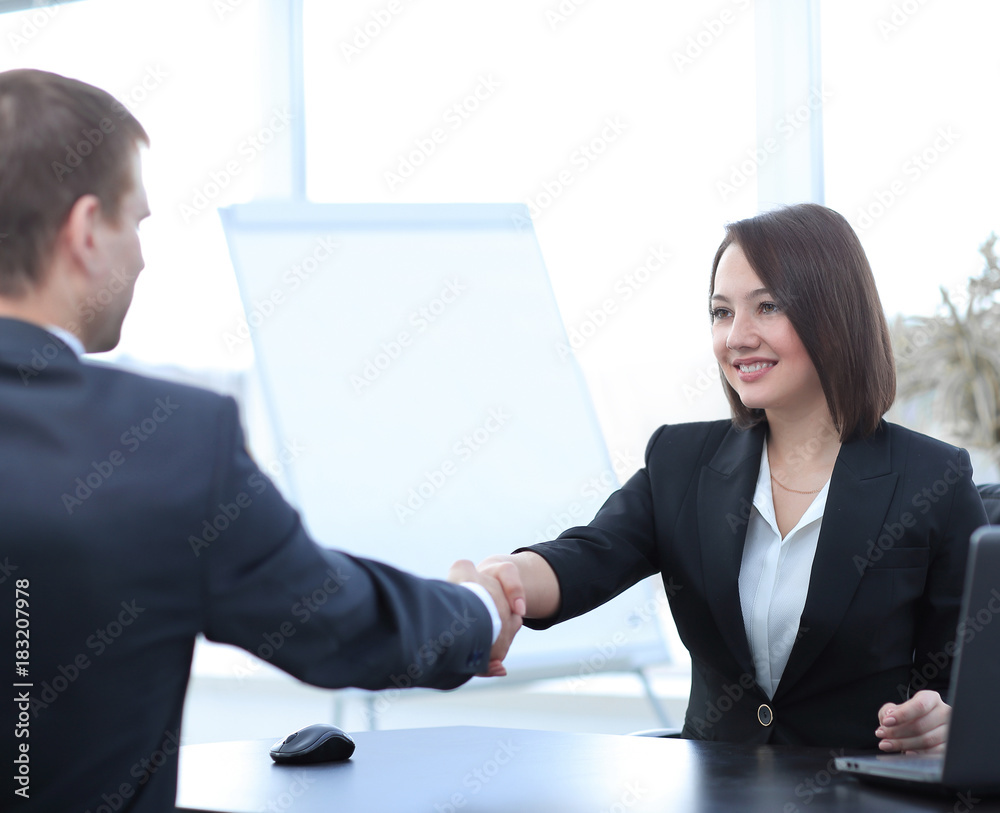 business woman shaking hands with a business partner over a Desk business woman shaking hands with a business partner over a Desk