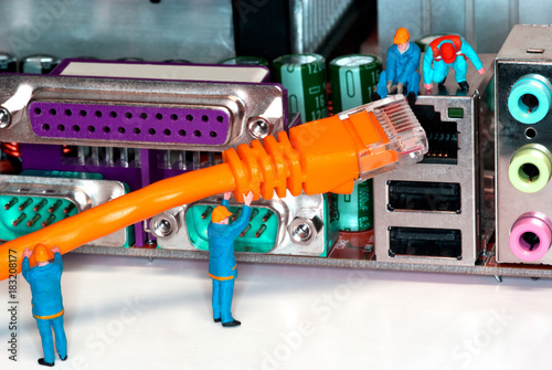 Computer Network Internet Cable - Miniature construction worker figurines posed as if working on a network connection.
