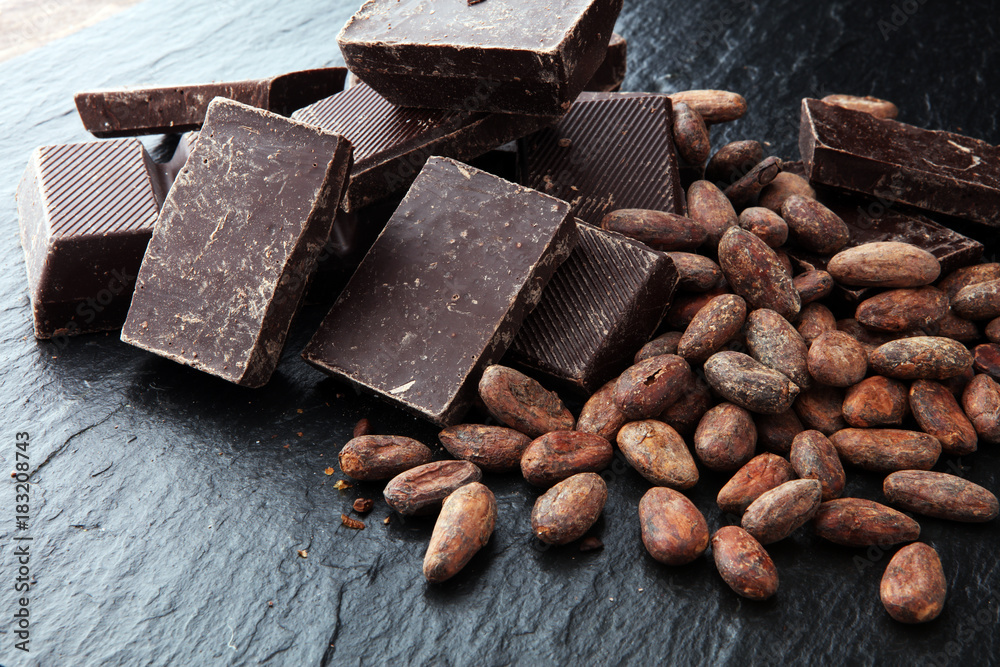 Dark chocolate pieces, stacks and cocoa beans, culinary background.. Dark chocolate pieces, stacks and cocoa beans, culinary background..