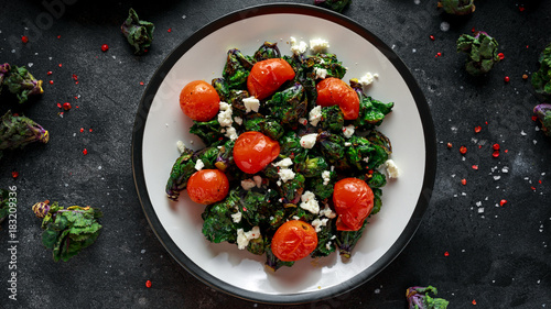 Homemade Roasted Green Kalettes salad with cherry tomatoes and feta cheese. healthy food photo