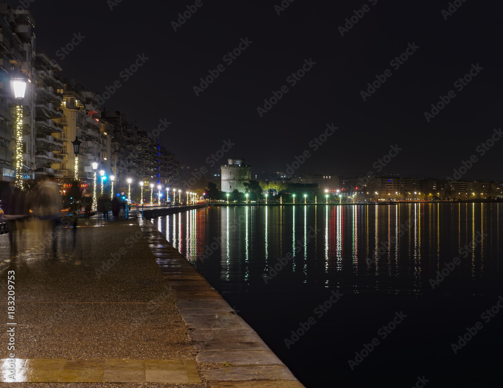 Fototapeta premium Thessaloniki, Greece night view of The White Tower and surrounding waterfront. The city's landmark seen from Christmas illuminated old waterfront area. 