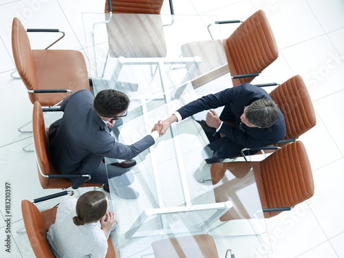 Handshake across the table. Meeting around a boardroom table.