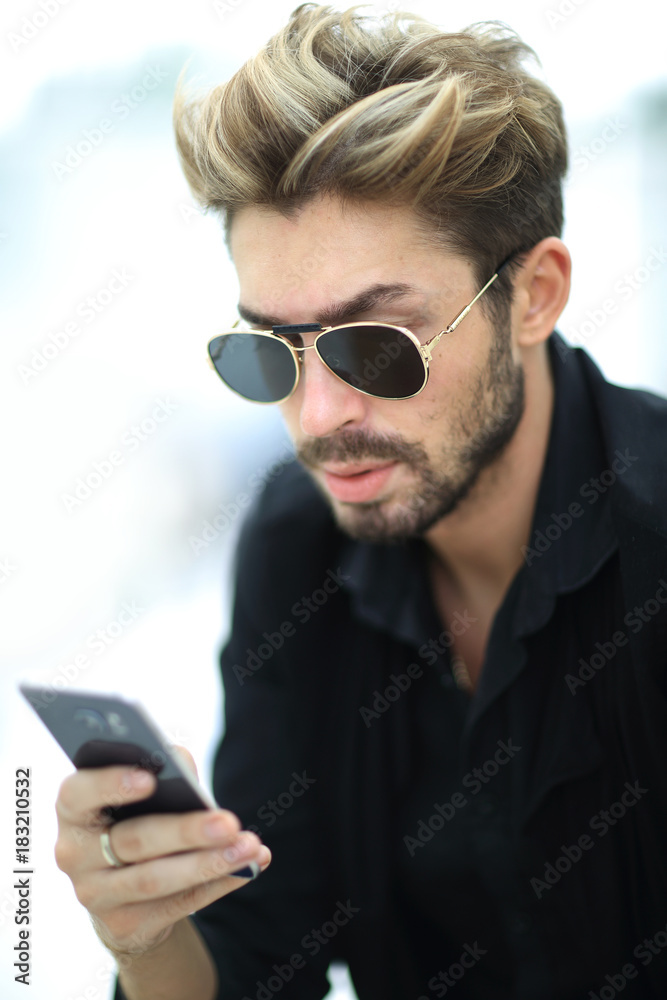 A stylish bearded male sits and uses a smartphone. A stylish bearded male sits and uses a smartphone.