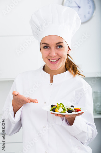 portrate of young coosie woman showing salad at kitchen photo