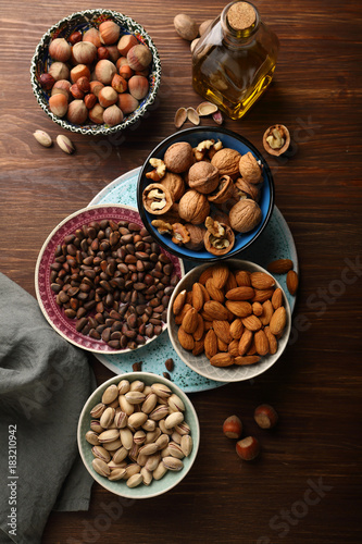Assorted nuts in bowls on wood background