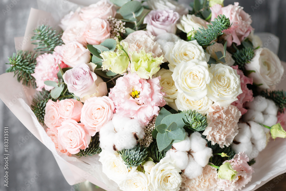 beautiful bouquet of mixed flowers into a vase on wooden table. the work of the florist at a flower shop beautiful bouquet of mixed flowers into a vase on wooden table. the work of the florist at a flower shop