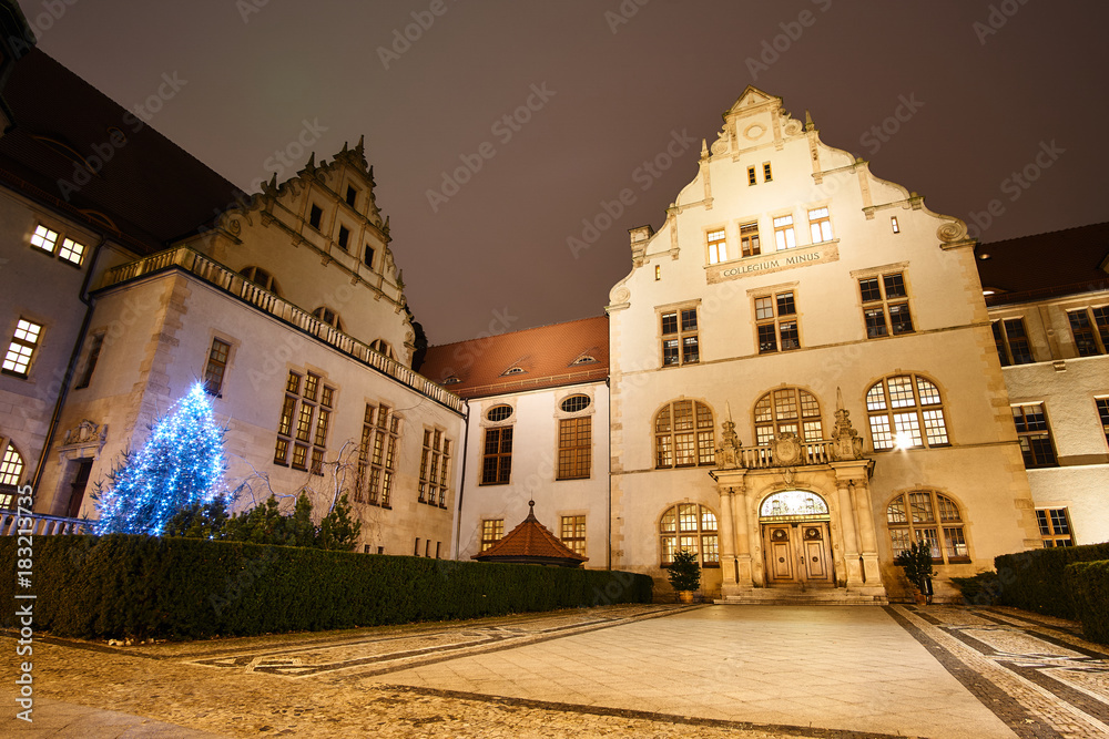 Christmas tree and facade of the neo-renaissance building of the university hall at night in PoznaÅ„.