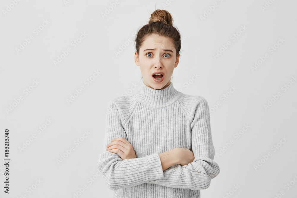 Portrait of indignant adult girl standing in closed posture with