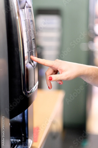 Female finger with manicure on button of coffee grade in coffee machine