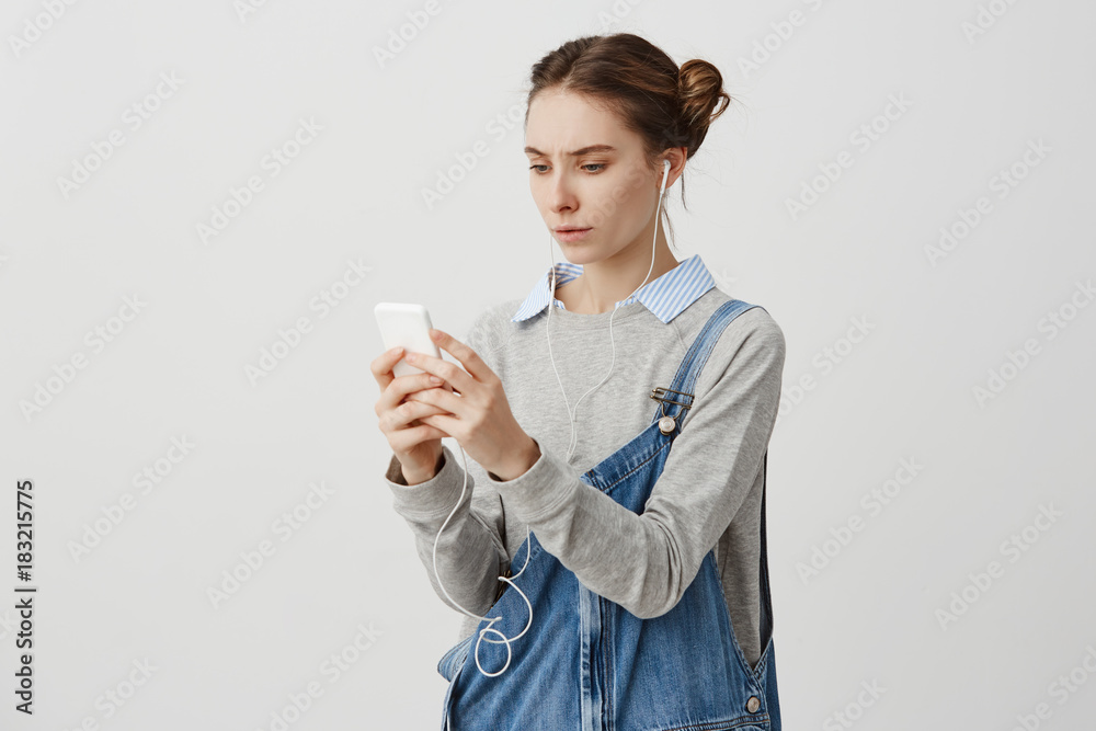 Puzzled young woman frowning having problem with her gadget Puzzled young woman frowning having problem with her gadget