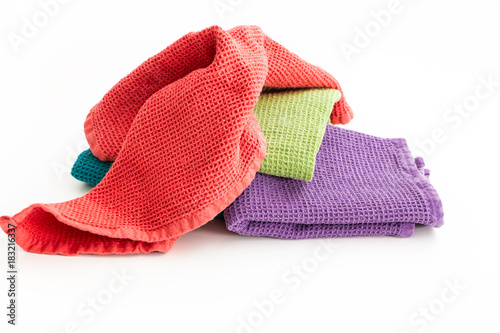 Pile of messy and folded colorful kitchen towels, on white background.