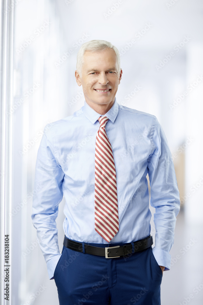 Financial business man. A senior financial consultant businessman standing in shirt and tie in his office.