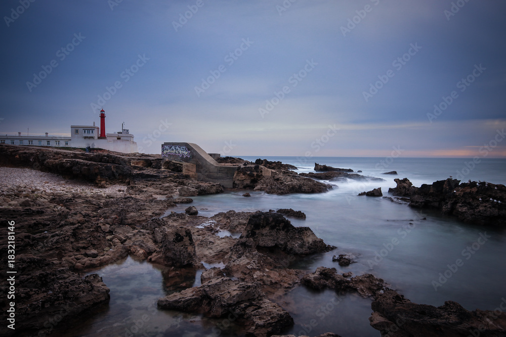 Long exposure from a lighthouse in a rocky beach in a cloudy winter day. Cascais, Portugal