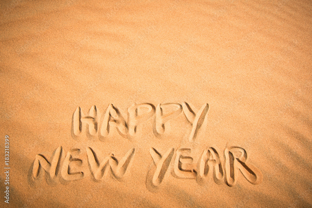 Happy New Year background. Handwriting in tropical sand.