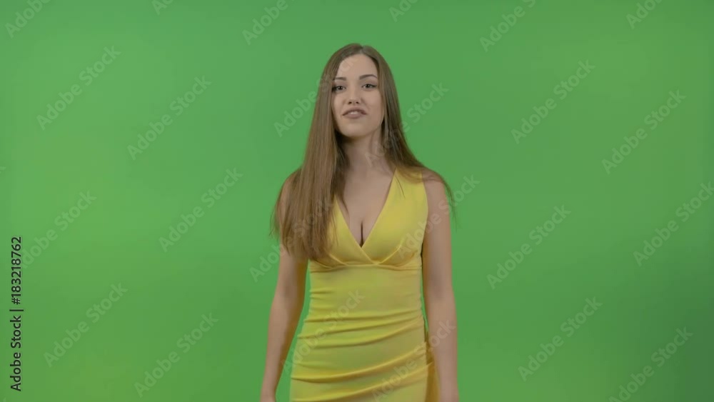 Beautiful young girl in a yellow dress, on a green screen. She turns and makes a gesture with her hand. Beautiful young girl in a yellow dress, on a green screen. She turns and makes a gesture with her hand.