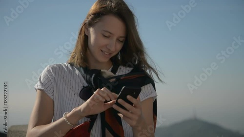 Woman with smartphone walking in the city at sunset. Steadicam shot