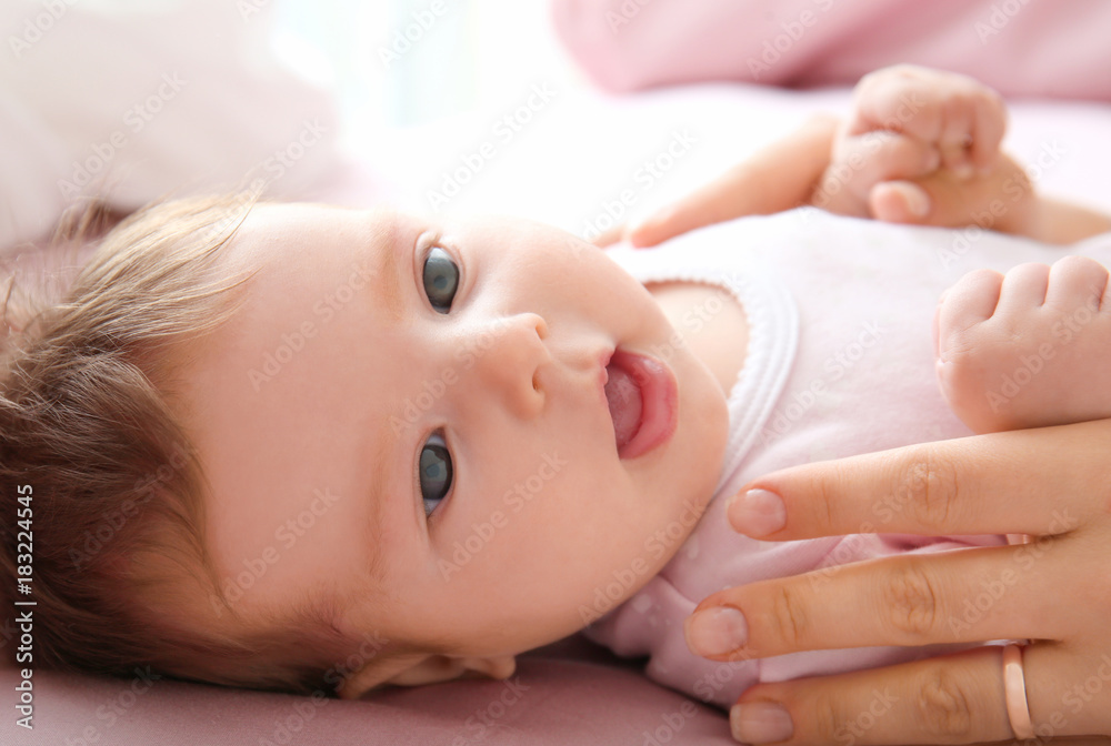 Cute little baby holding mother's hand on bed at home Cute little baby holding mother's hand on bed at home