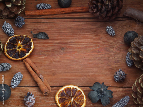 Wooden background with pinecones, cinnamon and tangerines. Top view.