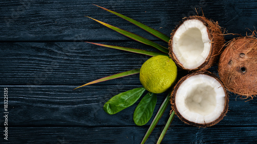 Fototapeta Naklejka Na Ścianę i Meble -  Coconut and lime. Fresh fruits. On a wooden background. Top view. Free space for text.