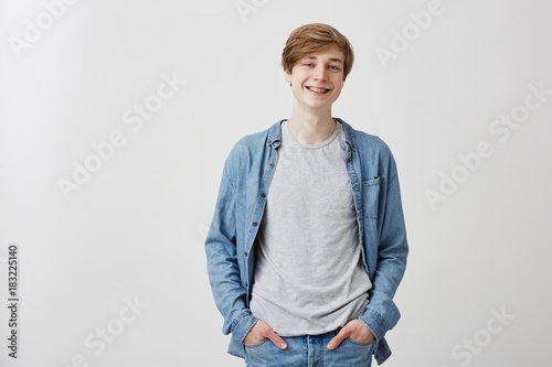 Картината върху платно Positive fair-haired male with blue eyes and braces smiles gently as being glad after date with grifriend