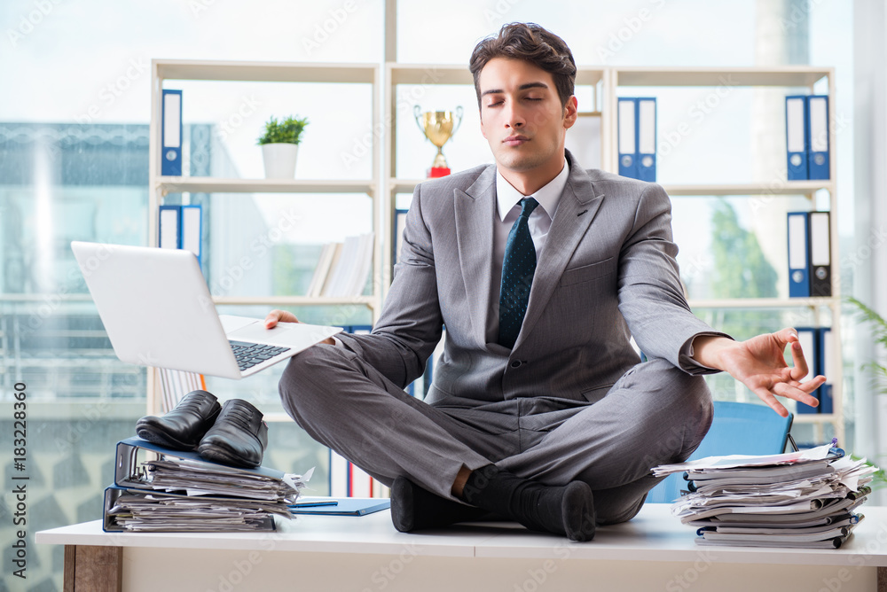 Businessman sitting on top of desk in office