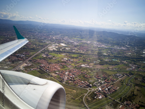 Aerial view to Italian countryside from the airplane window. Wing with engine.